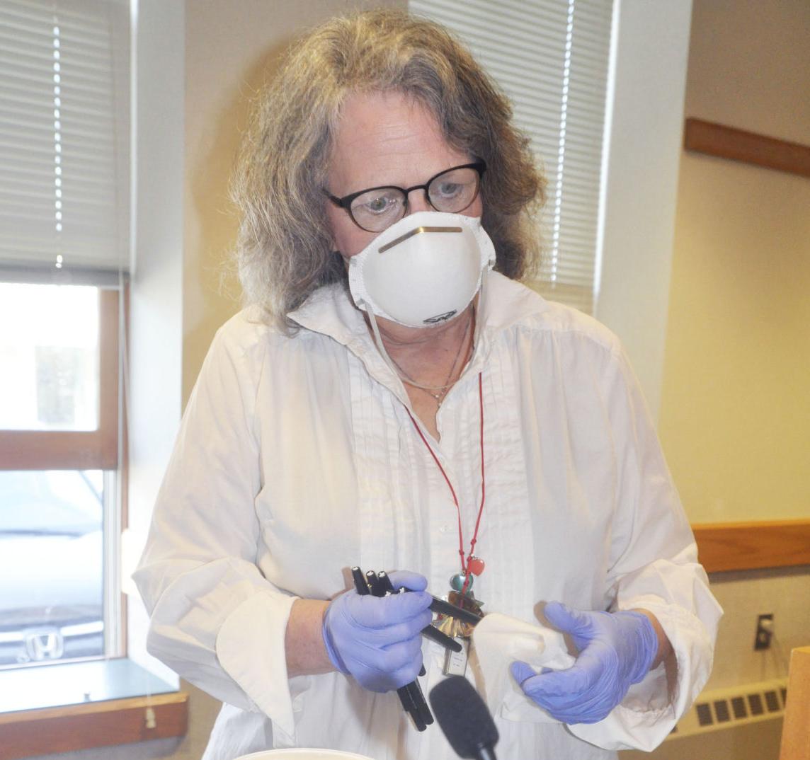 Poll worker sanitizes pens after each use on Election Day